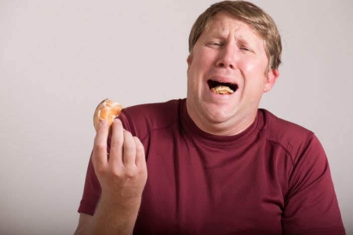 ドーナッツがまずくて悲しそうな太った男性の写真